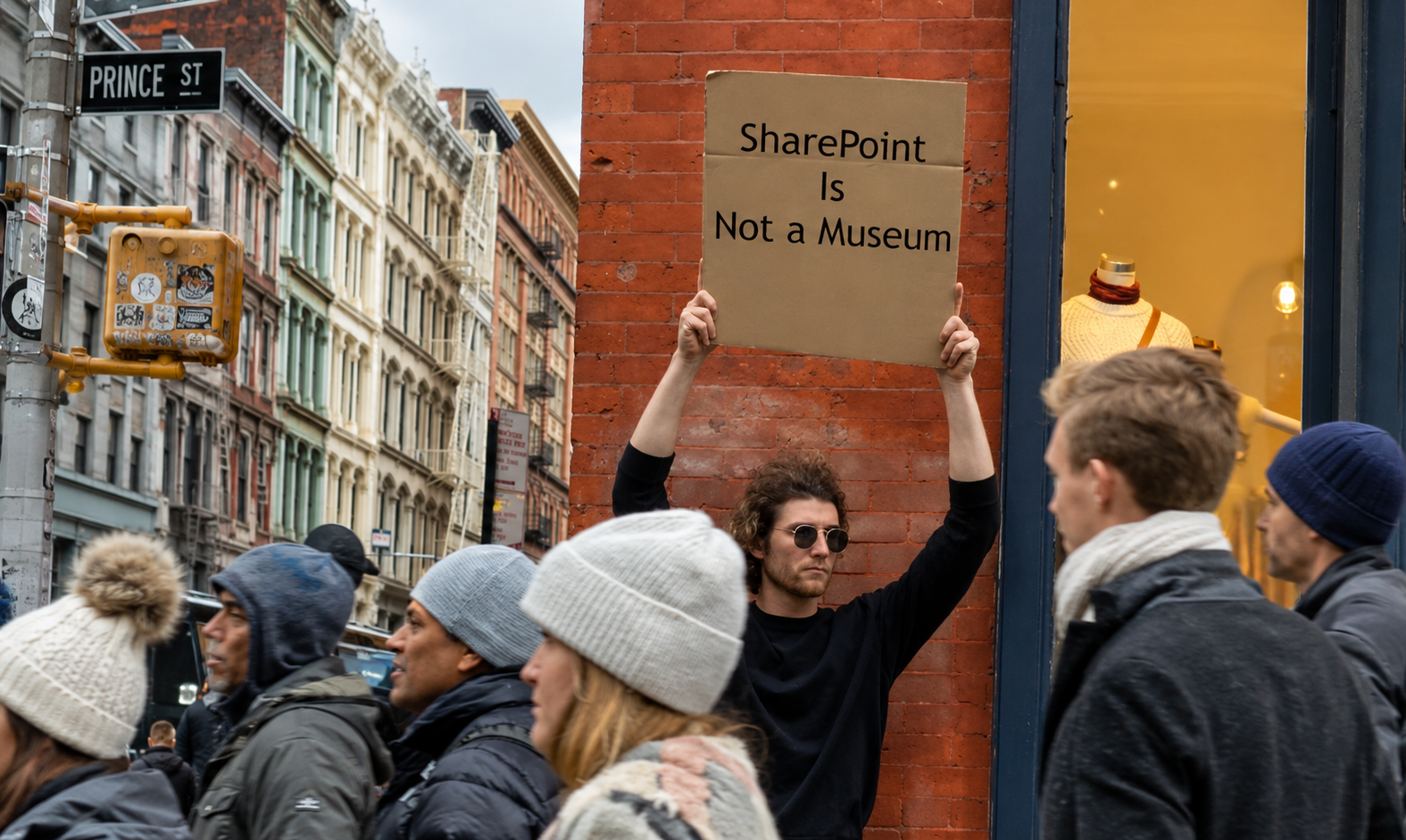 Person holding a cardboard sign that reads SharePoint Is Not a Museum on a city street.
